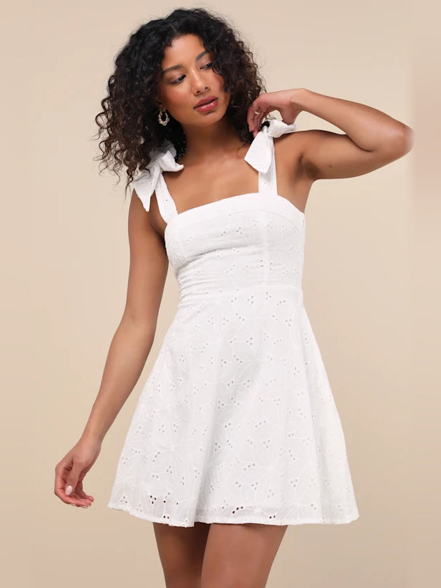 White embroidered mini dress with square neckline, bow shoulder straps, flared skirt