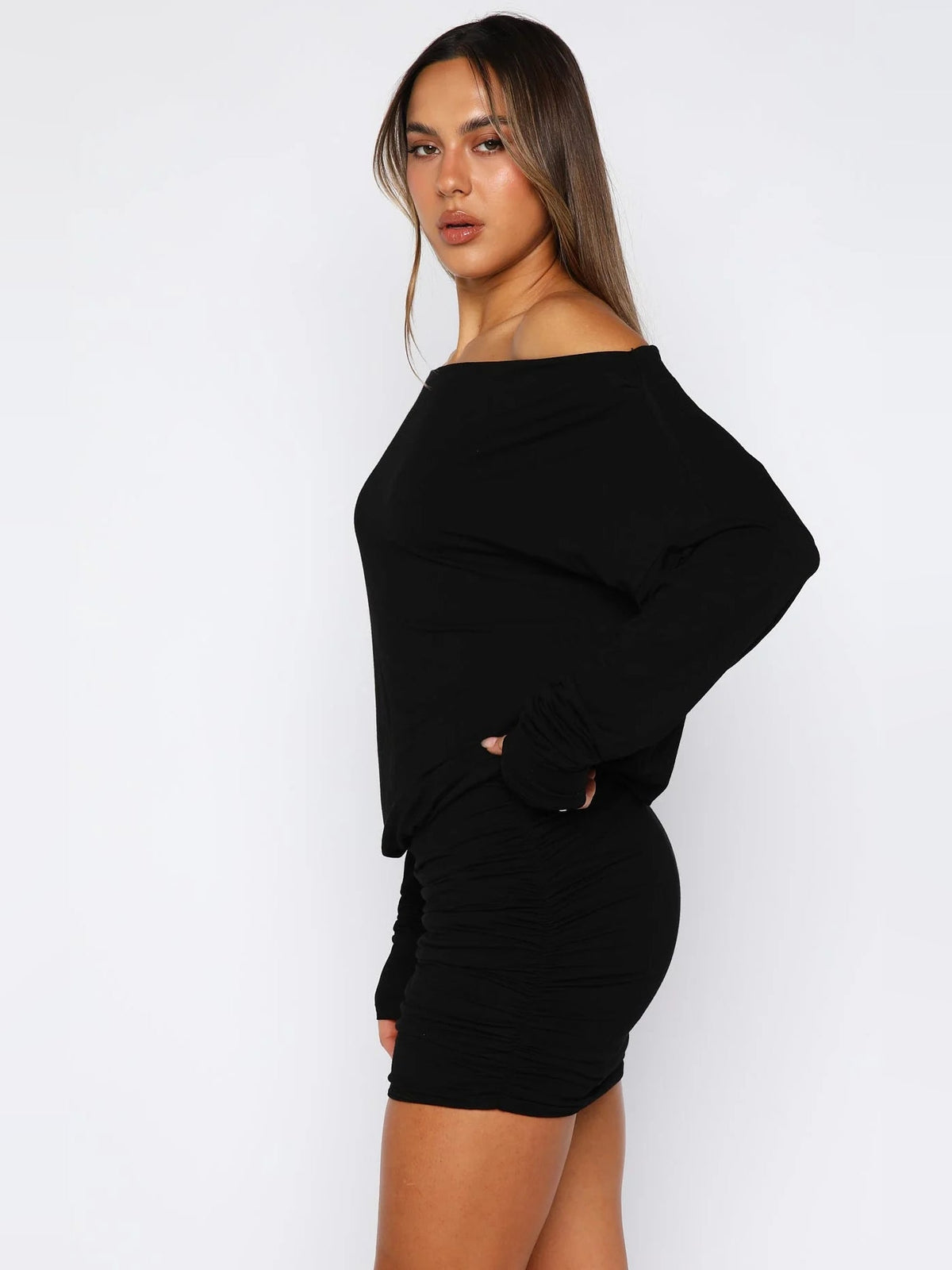 Black off-shoulder long-sleeve mini dress with gathered ruched waist and short hem.