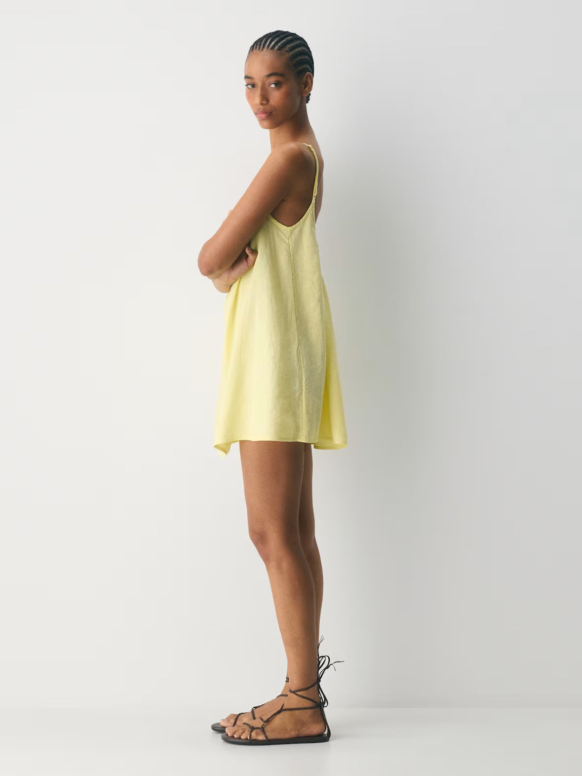 Light yellow mini dress in sleeveless tank style with thin straps and curved hem