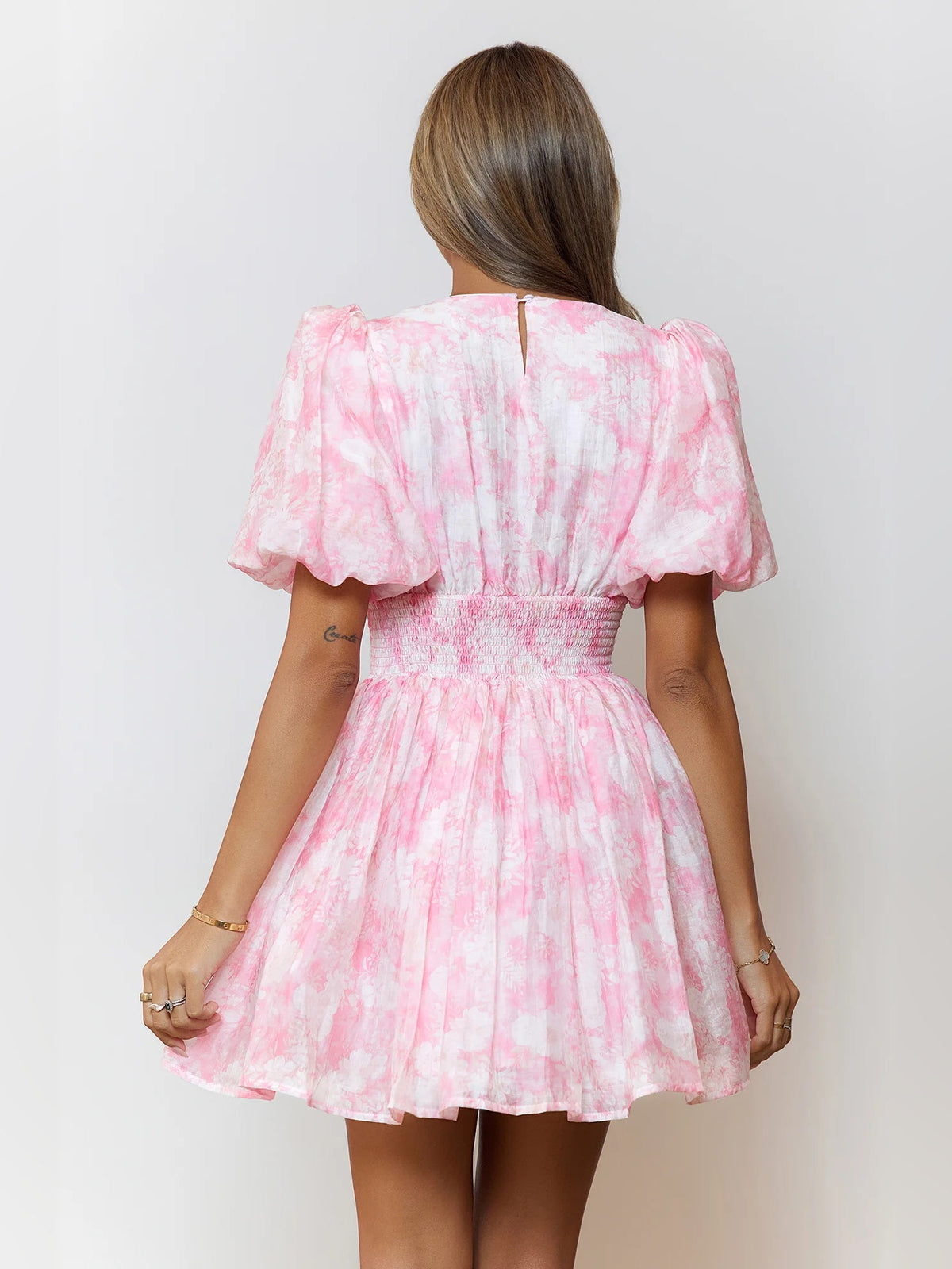 Pink back-view mini skater dress with puff sleeves and cinched tie waist