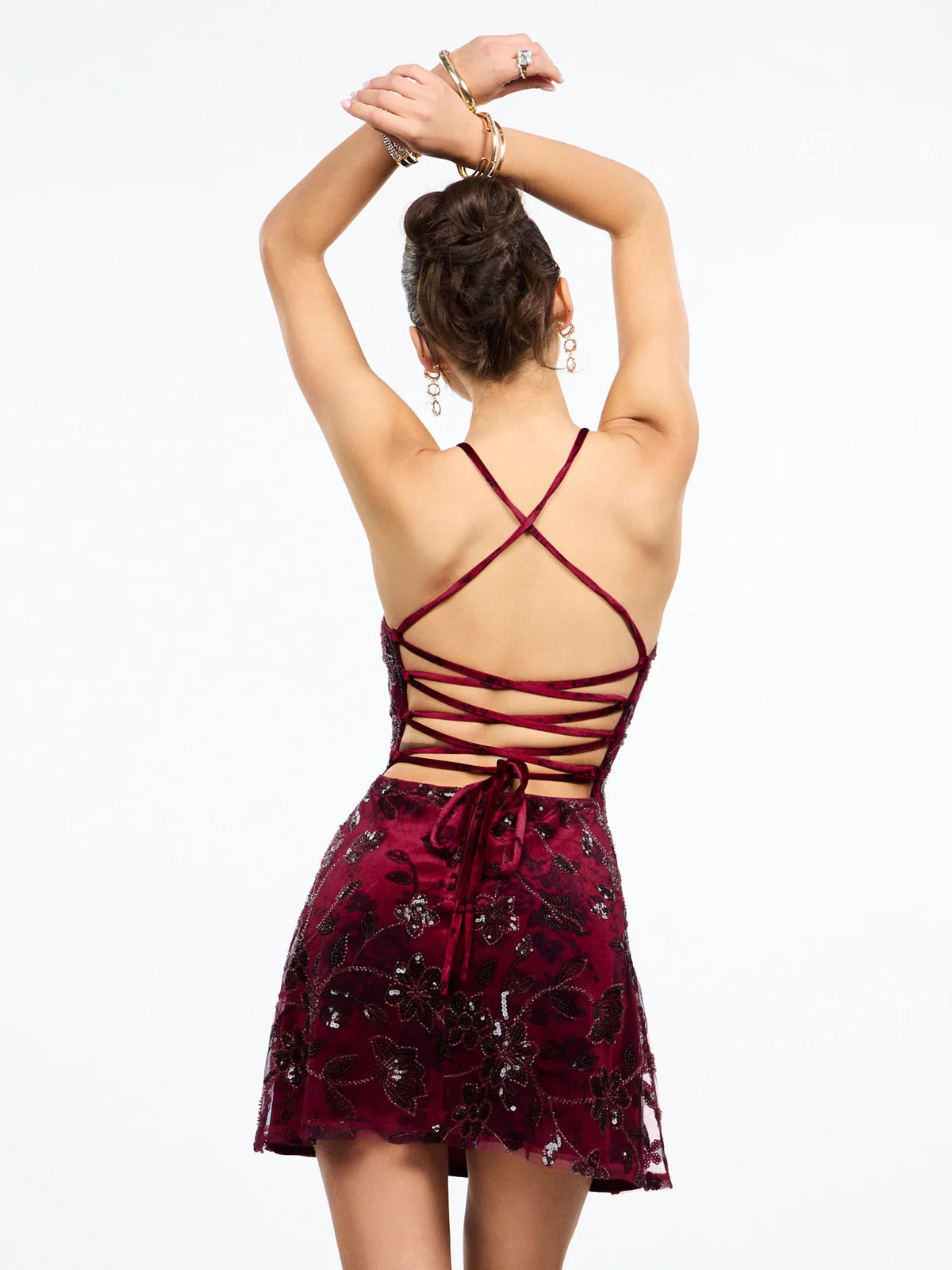 Burgundy sequin mini dress with crisscross back straps and lace-up detailing.