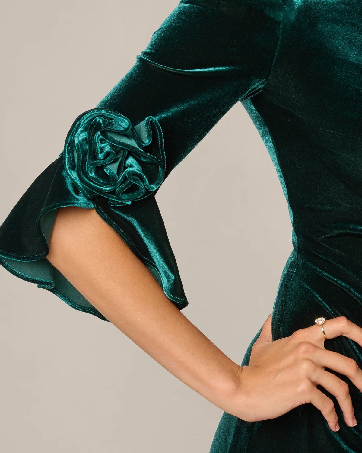 Close-up of hunter green off-shoulder dress sleeve with rosette flower detail