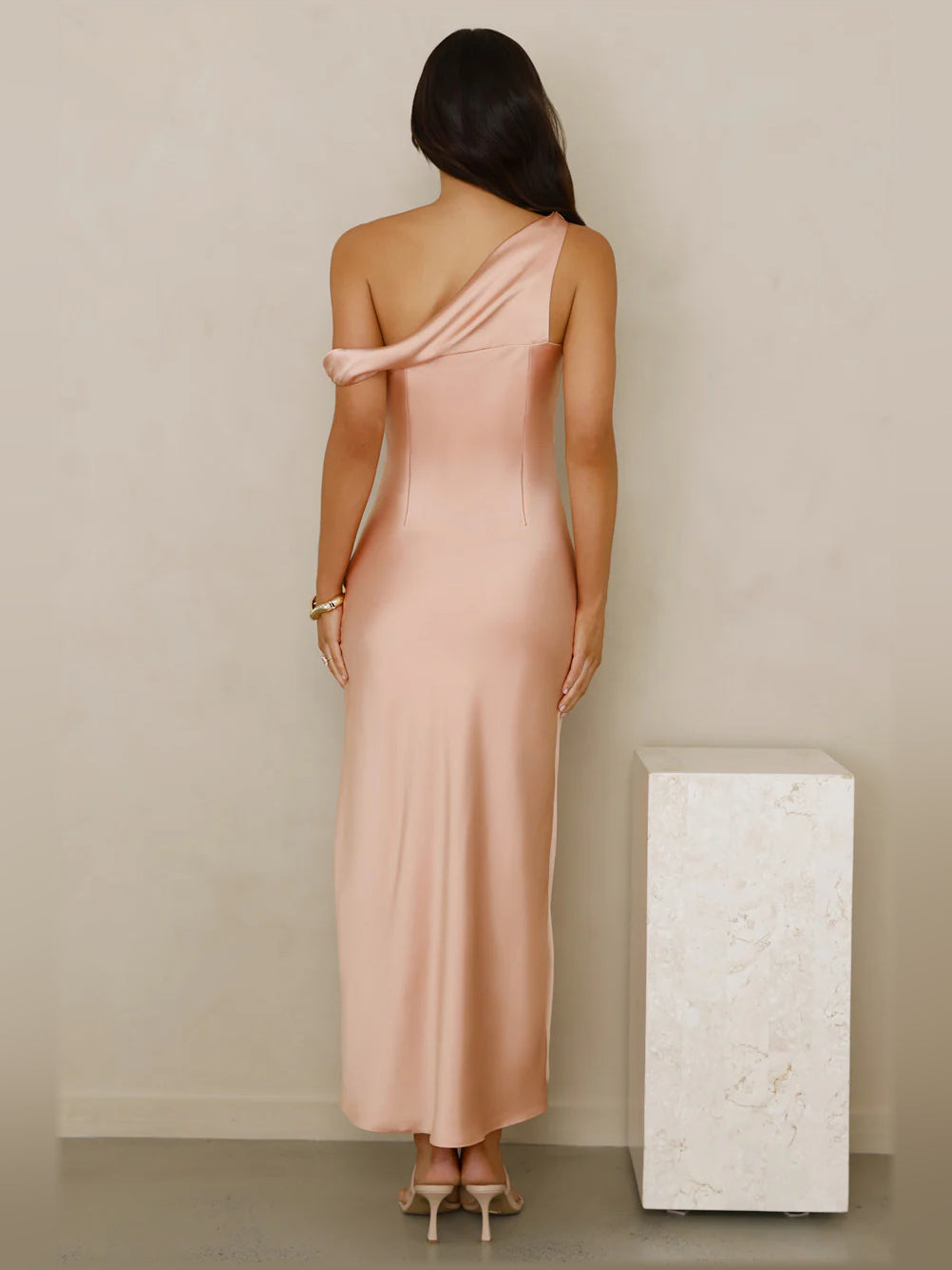 Back view of peach satin off-shoulder midi formal dress with crossed drape strap