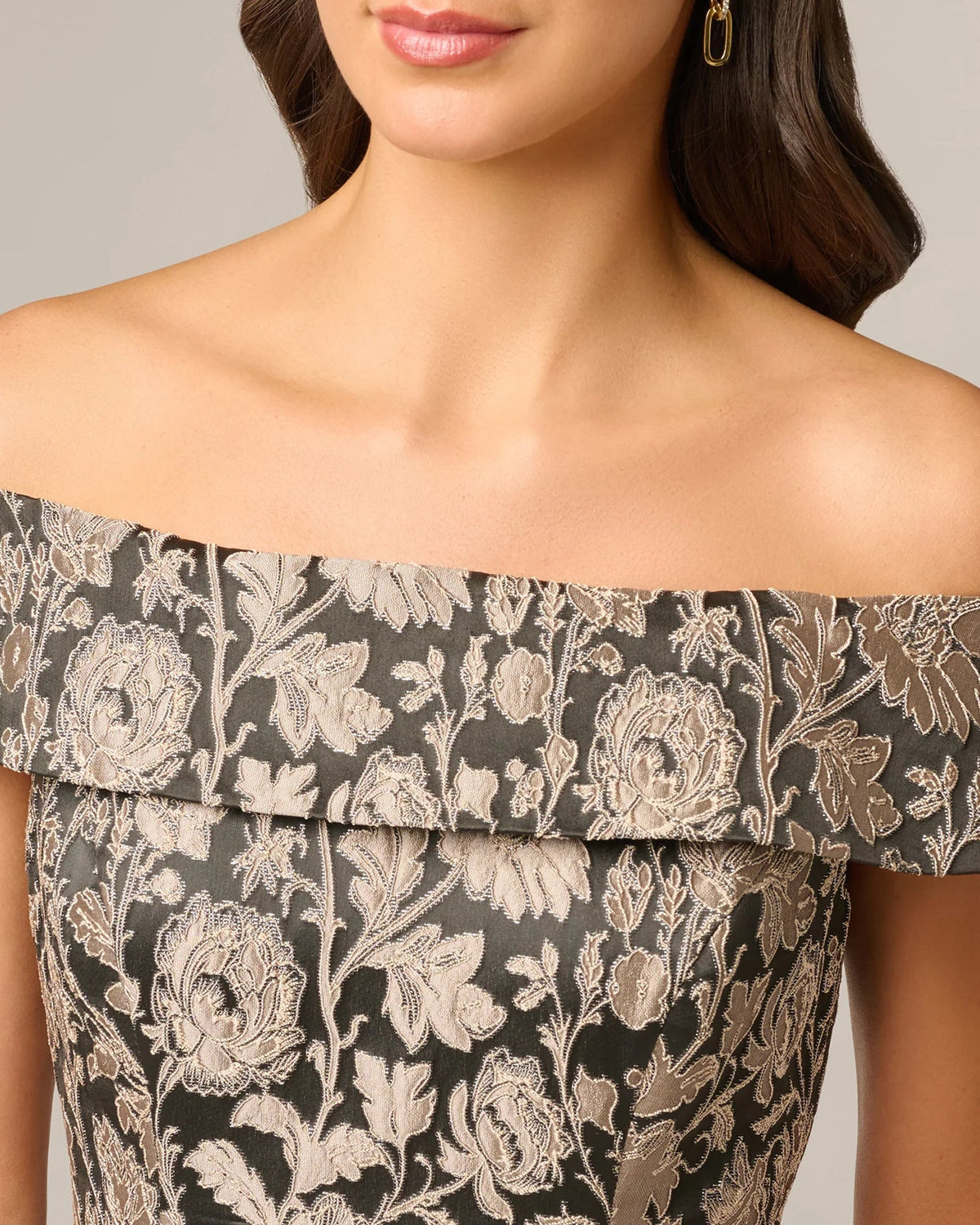 Close-up of off-shoulder neckline with taupe floral embroidery on black fabric