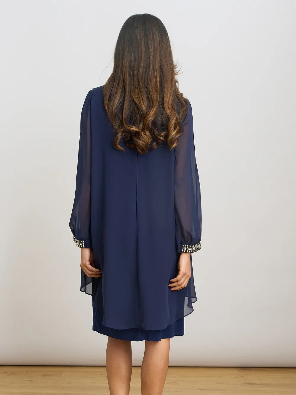 Dark navy chiffon sheath dress shown from back with bead-trim cuffs and draped back panel