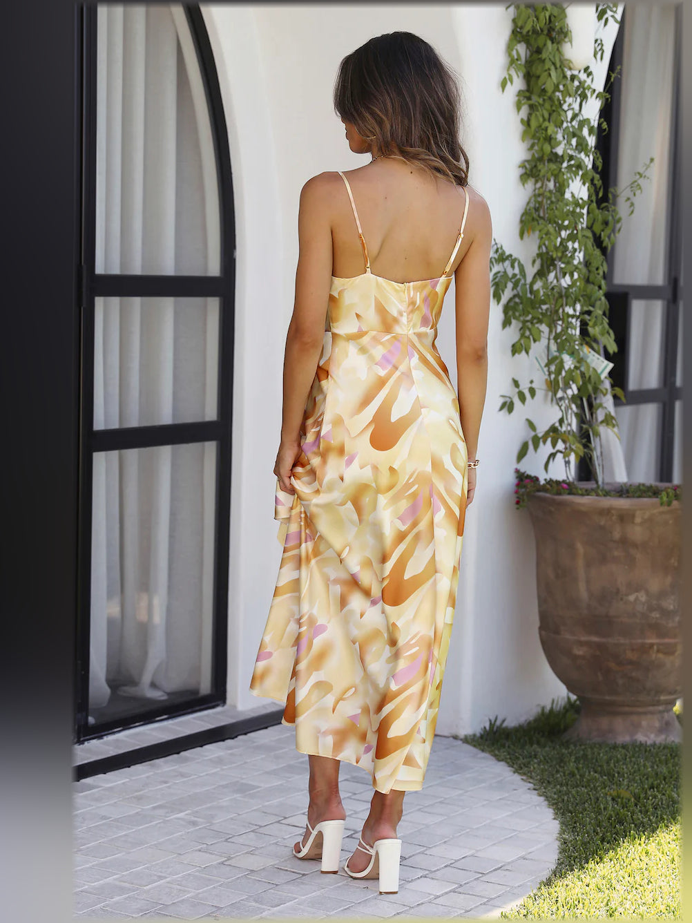 Back view of yellow-and-cream satin midi dress with spaghetti straps and ruched drape