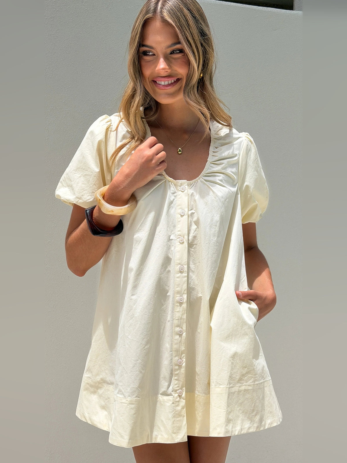 Butter button-front mini dress with short puff sleeves and rounded neckline, close-up