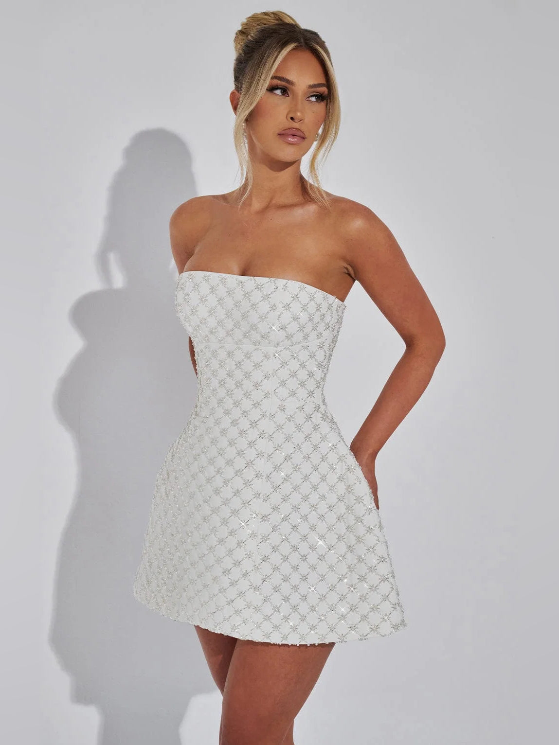 Ivory strapless mini dress with textured pattern, fitted waist and flared A-line skirt.