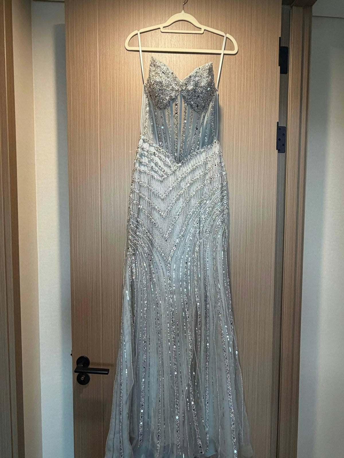 Silver beaded formal dress on hanger, sweetheart corset bodice, slit front.