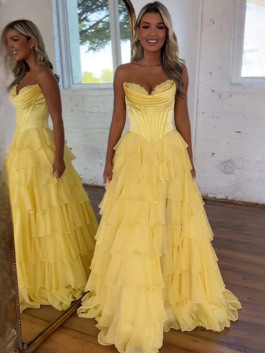 Yellow strapless sweetheart prom dress with ruched corset and tiered ruffle skirt.