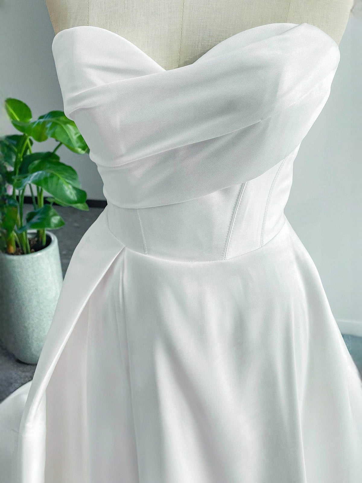 White strapless sweetheart satin bodice with draped neckline and structured waist seam