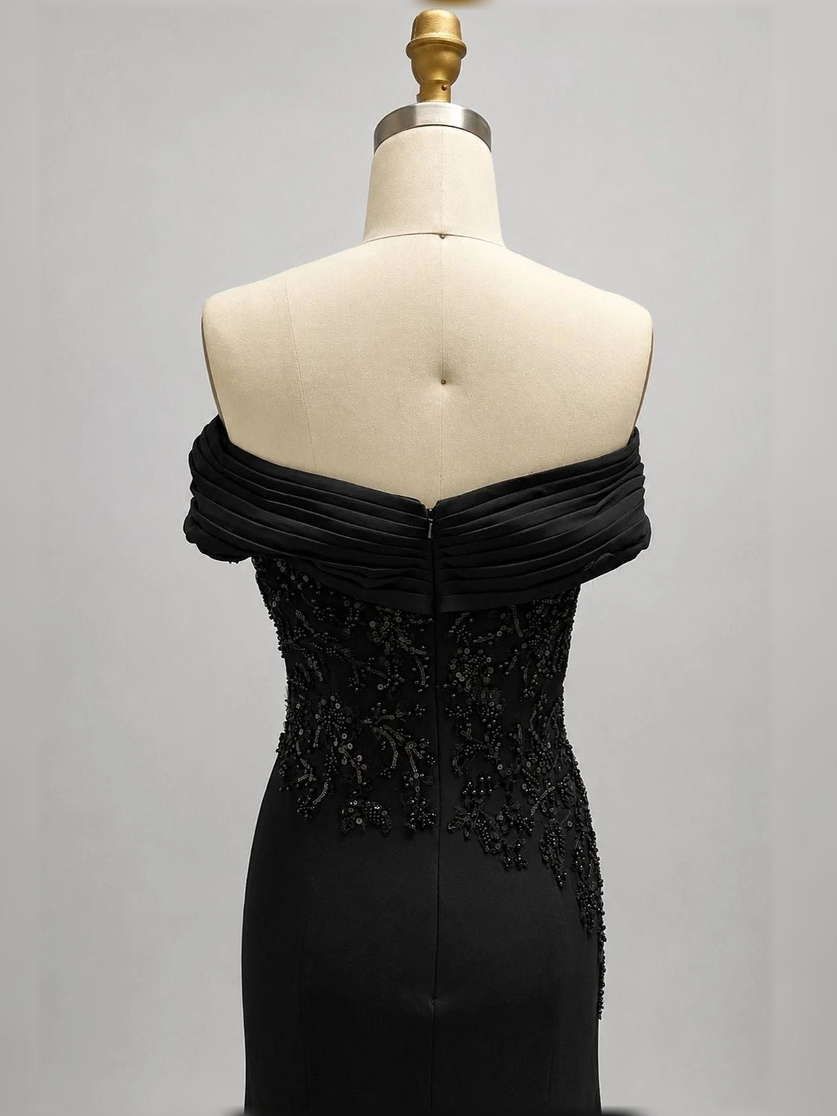 Black off-shoulder ruched gown close-up on mannequin, corset-style embellished bodice