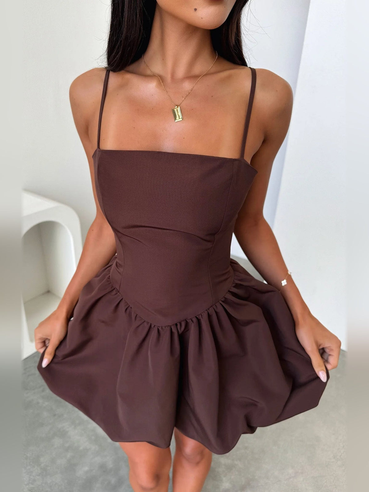 Brown square-neck mini dress with thin straps, fitted bodice, and gathered flared skirt
