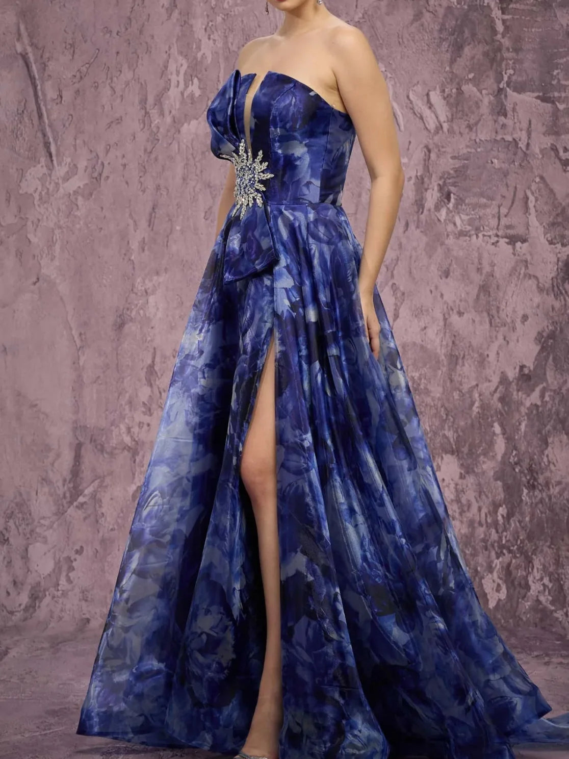 Navy strapless evening gown with side slit, pleated full skirt, and jeweled waist