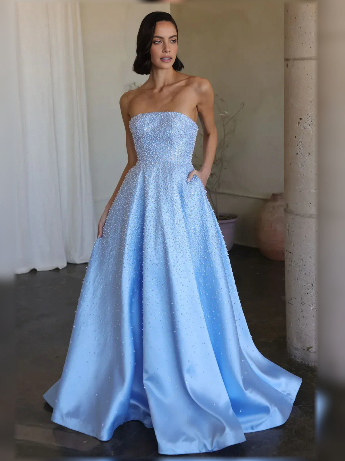 Light blue strapless beaded corset formal dress with cinched bodice and flowing skirt.