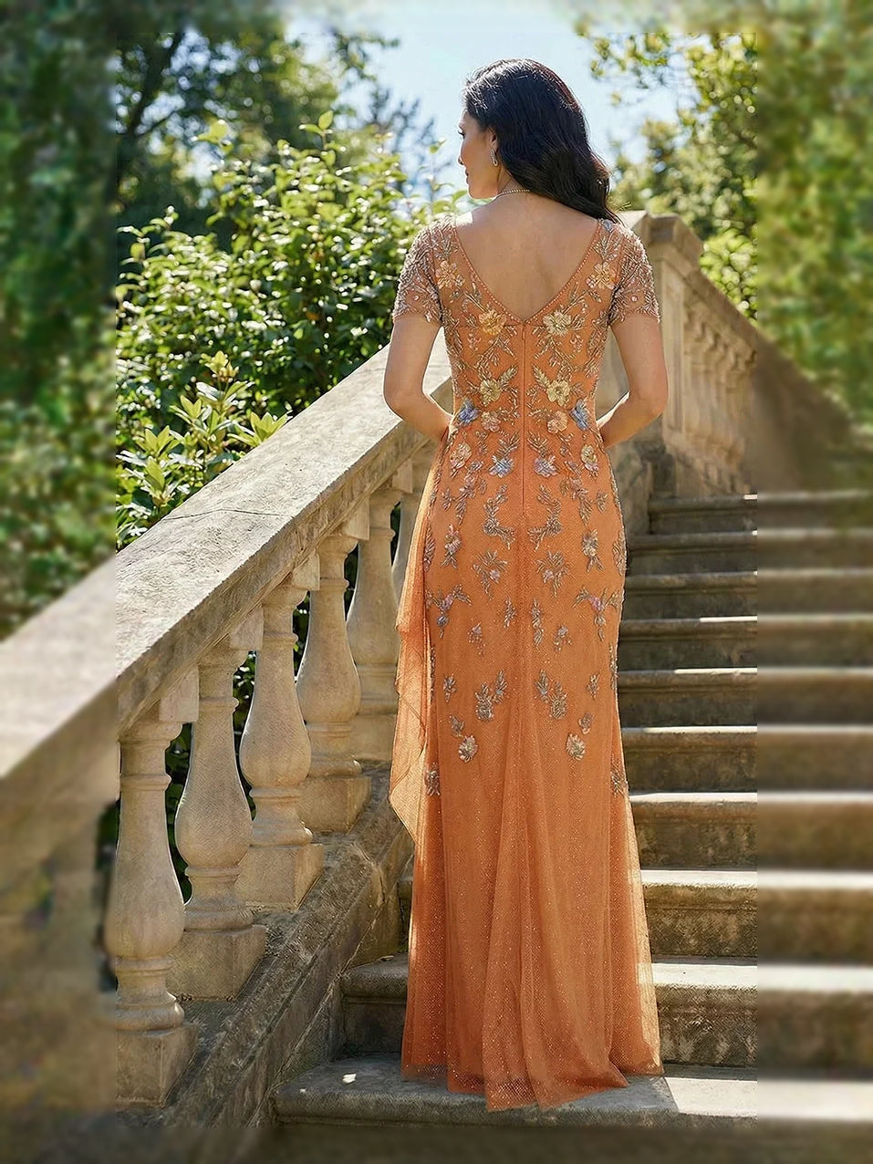 Orange chiffon mermaid dress viewed from the back with V-back and floral embroidery