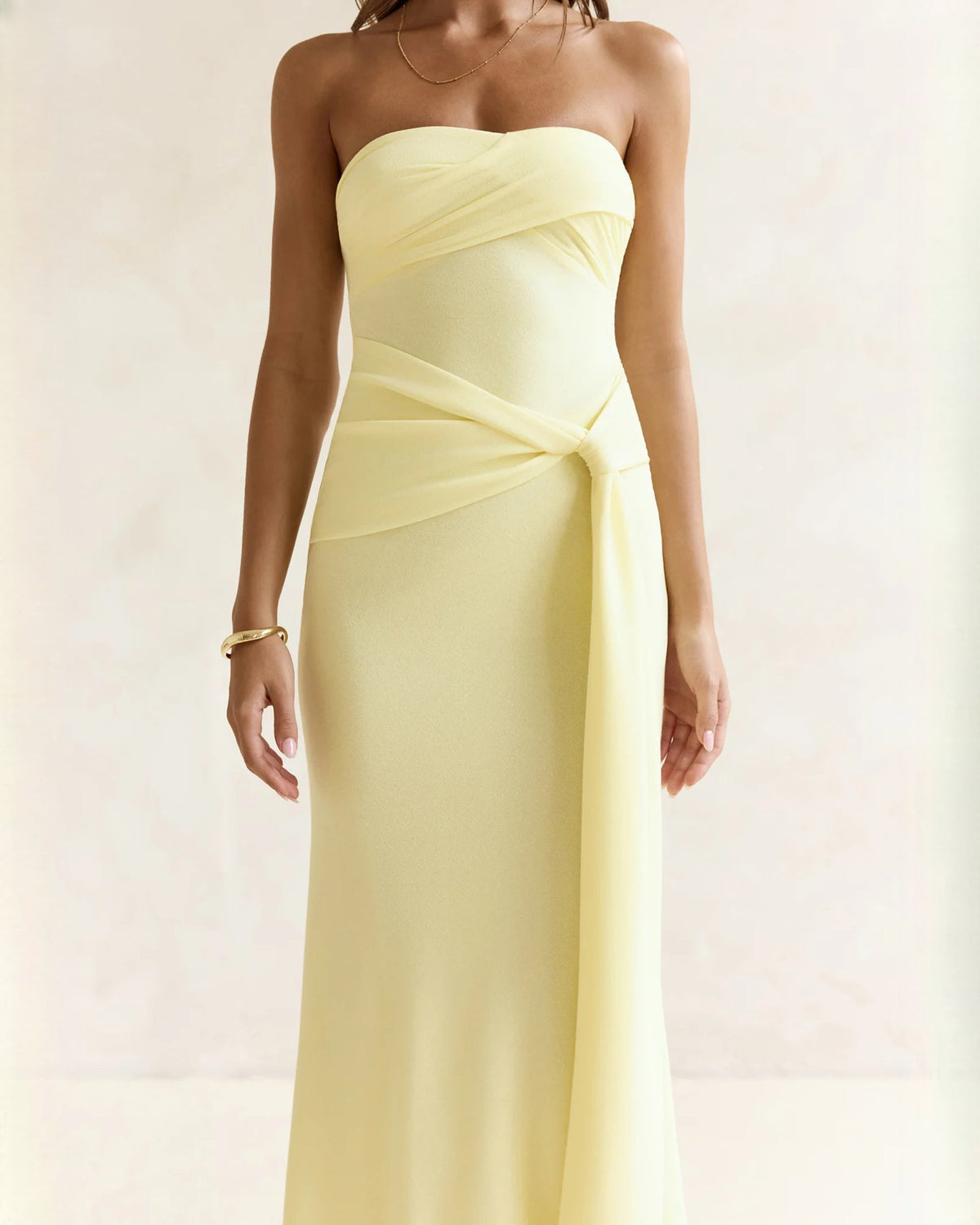 Light yellow strapless satin maxi dress with wrapped waist and soft pleated overlay