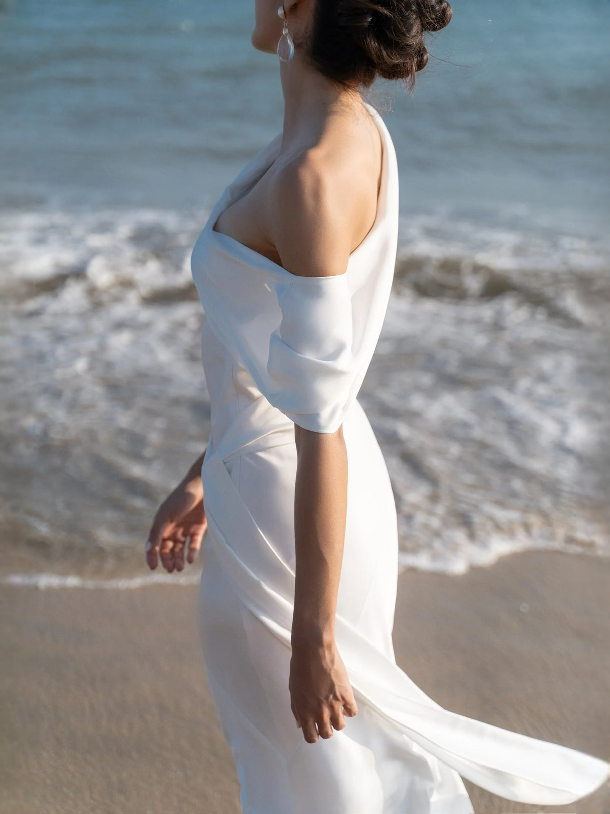 White satin dress with halter neckline and draped crossover back, fitted sheath silhouette