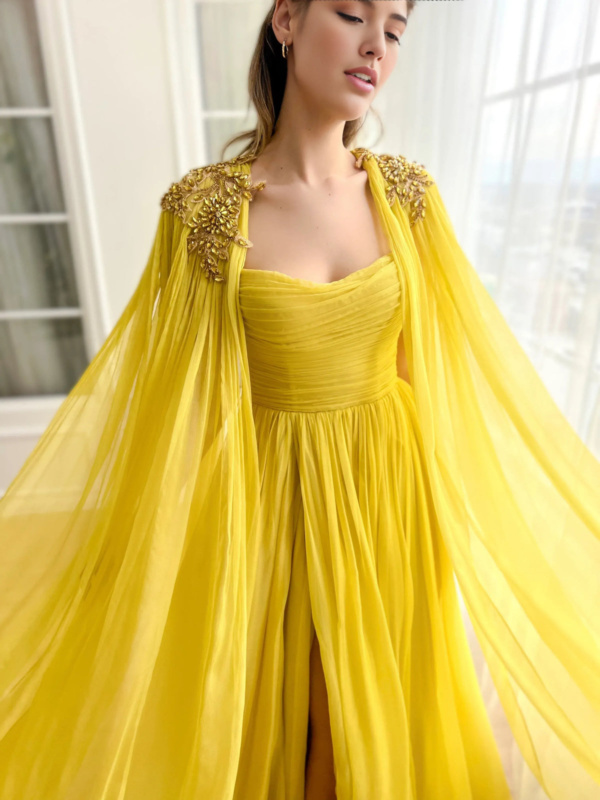 Yellow sweetheart formal dress with ruched bodice and gold-embellished tulle cape