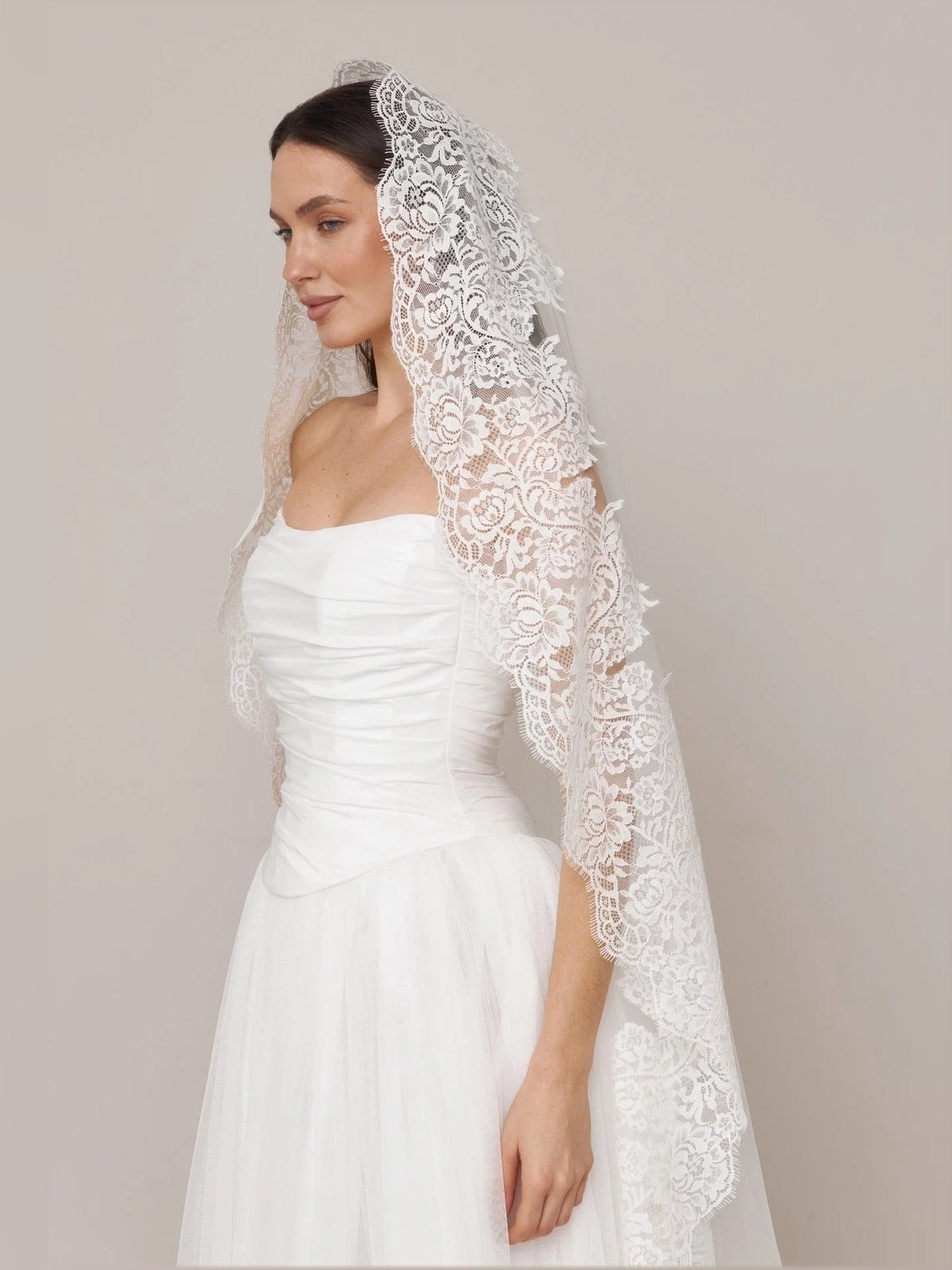 Ivory strapless wedding dress with ruched bodice and A-line skirt, lace draped veil detail