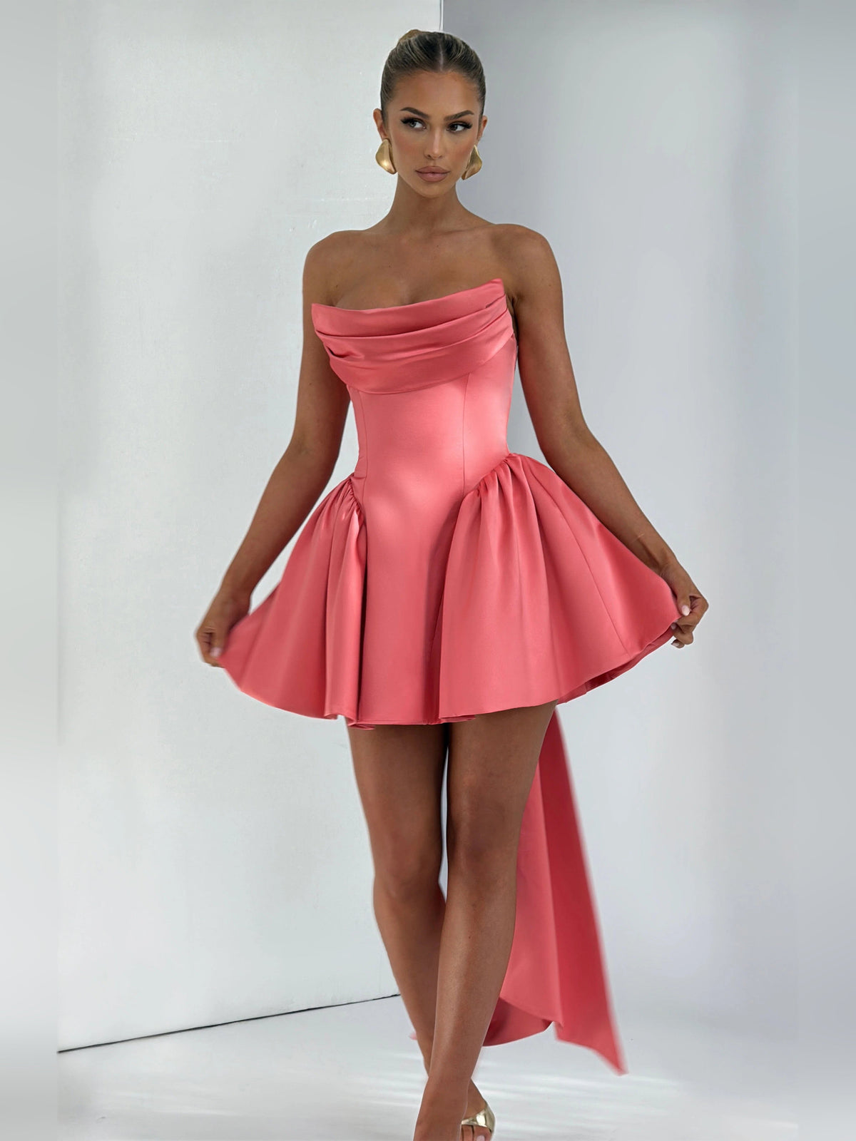 Pink strapless mini dress with ruched bodice, flared skirt, and long side panels