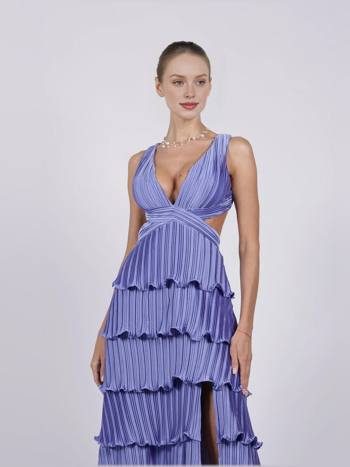 Purple v-neck pleated tiered formal dress with crisscross waist detail and thigh slit.