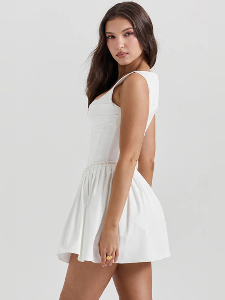 White pleated mini dress shown in side view with sleeveless square neckline