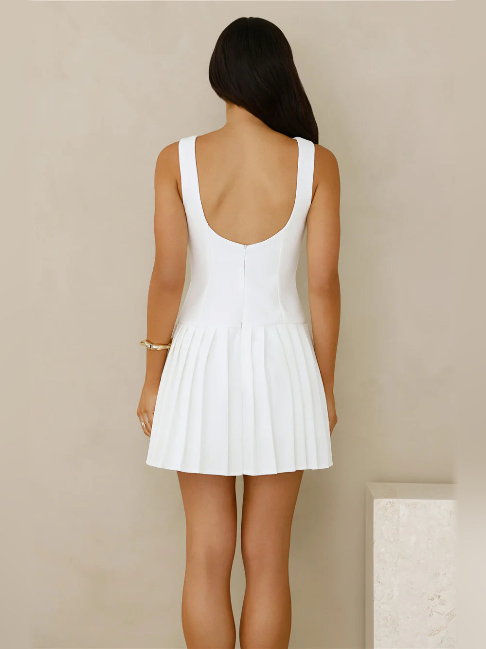 White sleeveless mini dress with scoop back and pleated skirt