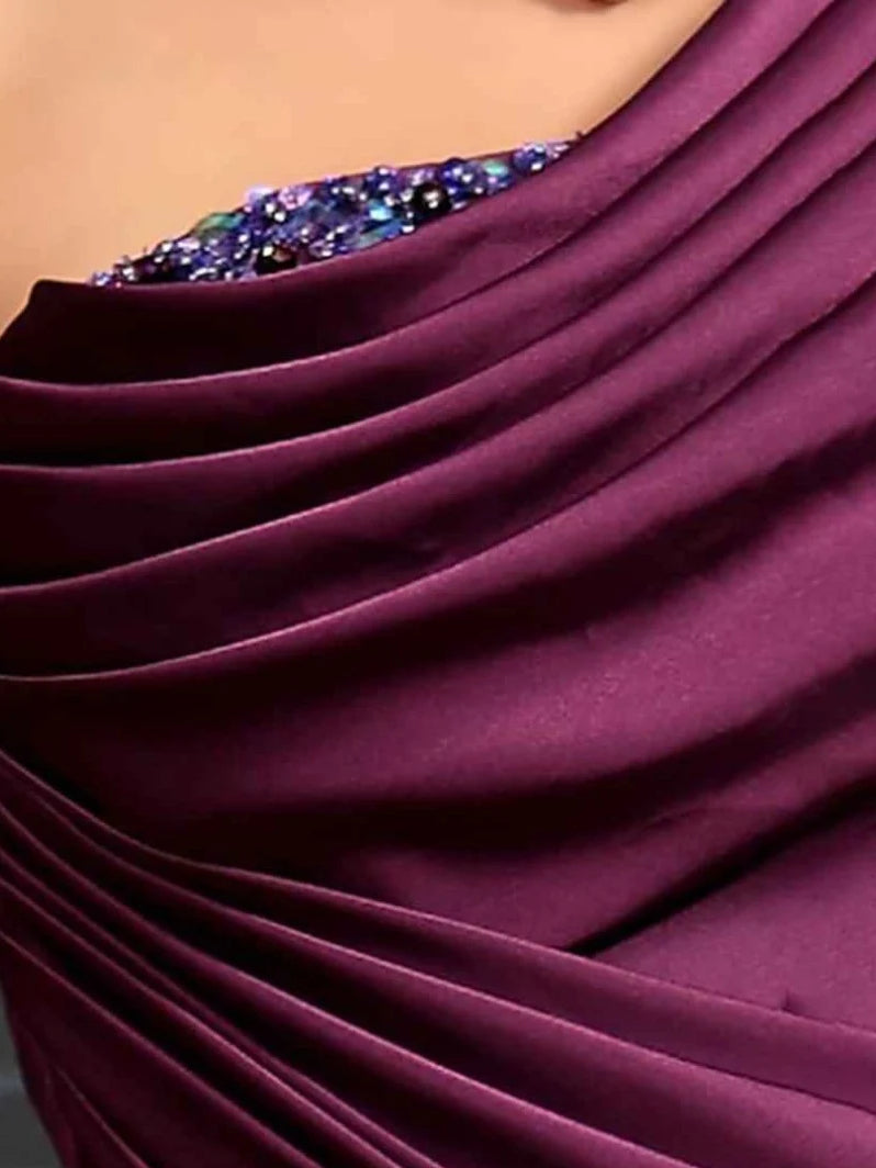 Plum one-shoulder dress close-up: ruched fabric folds and embellished neckline detail