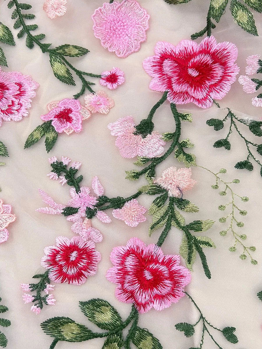 Embroidered floral appliques on sheer tulle with pink, red, and green threadwork