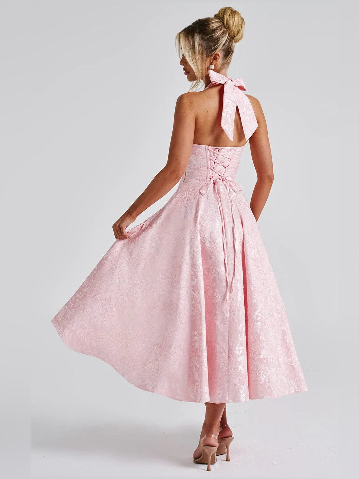 Blush halter midi formal dress from back view with open back and bow tie detail