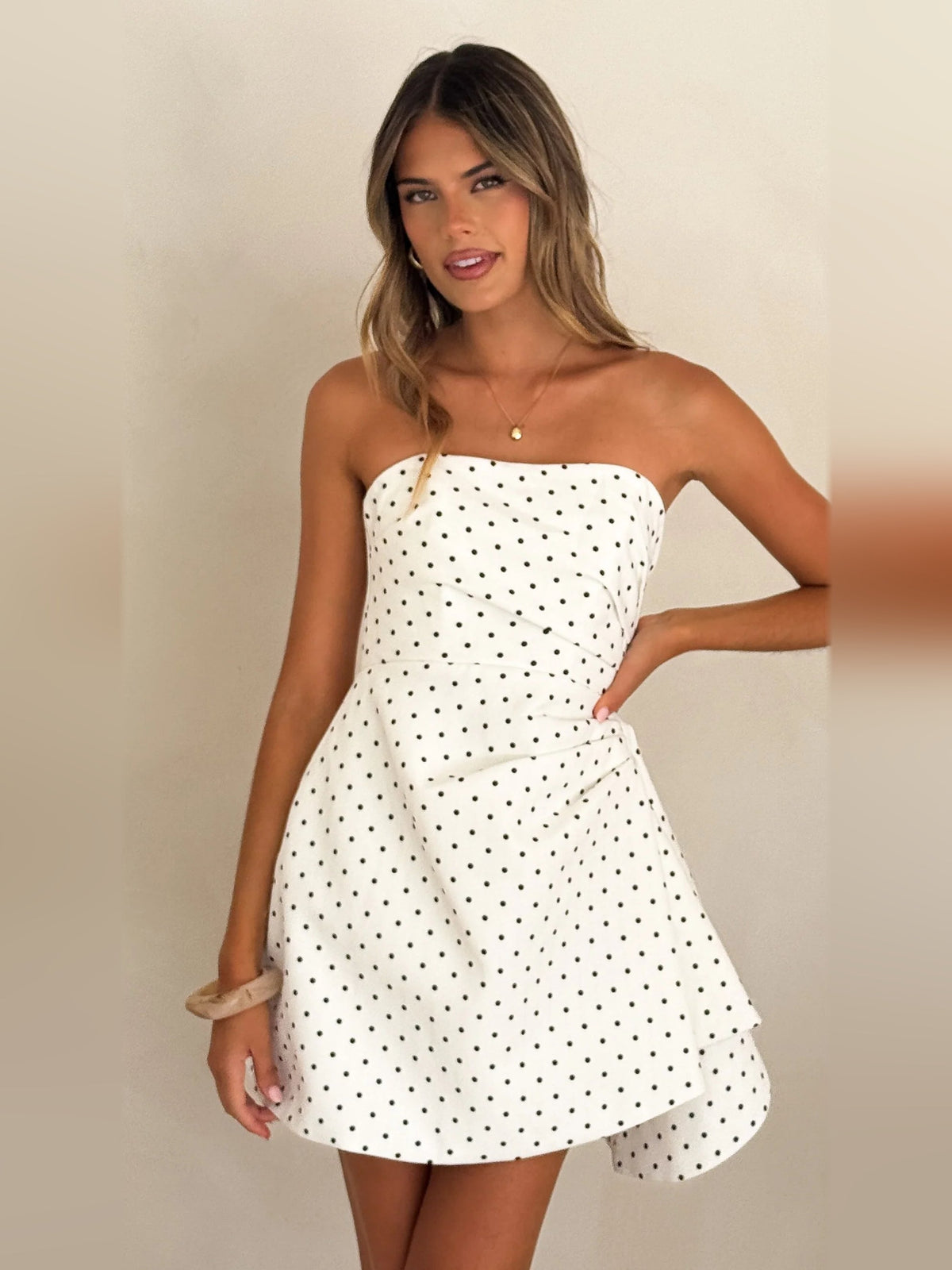 White strapless mini dress with black polka dots, gathered waist and flared skirt