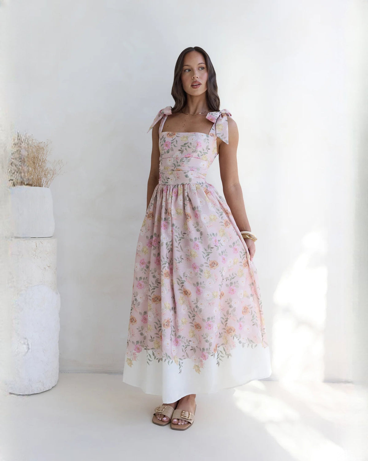 Front view of pink floral sleeveless satin A-line maxi bridesmaid dress with waist tie