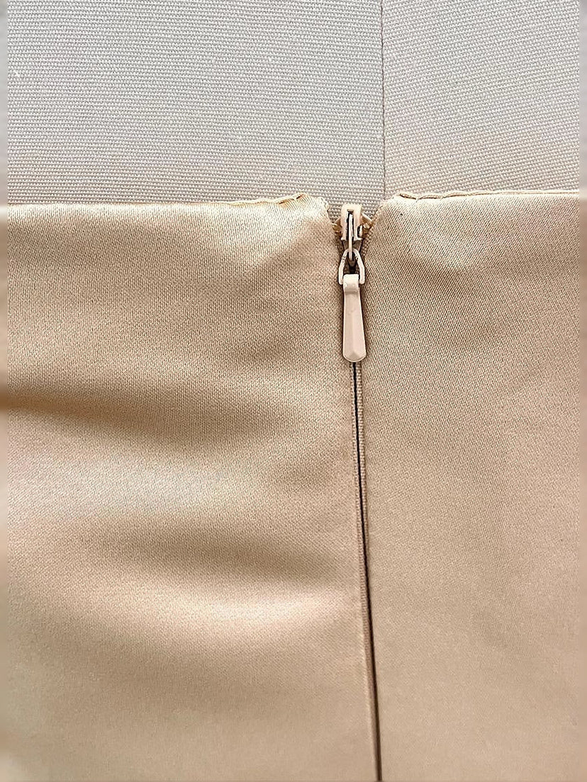 Gold satin dress back zipper close-up with metal pull and seam detail