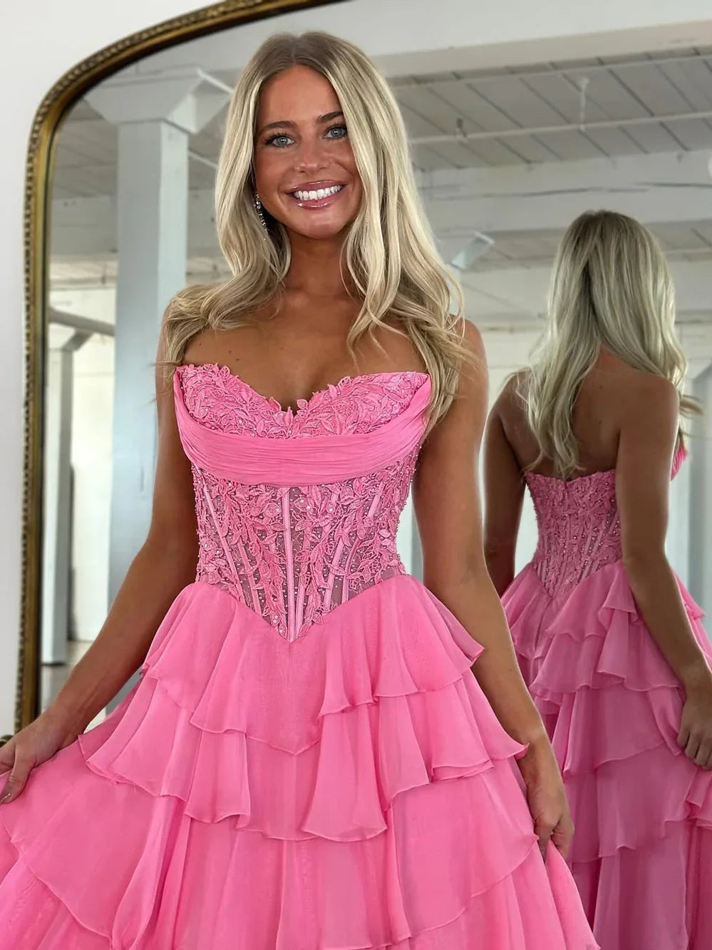 Pink strapless corset prom dress with lace bodice and layered tiered ruffles, high-low hem