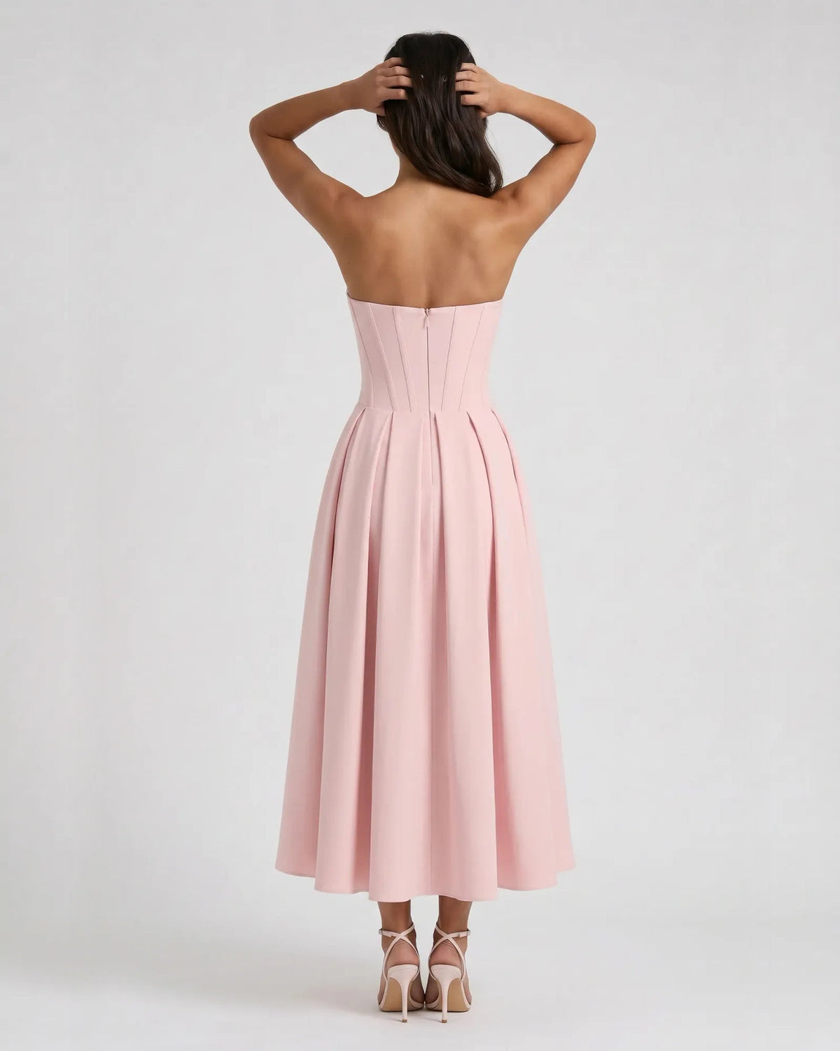 Back view of blush pink strapless sweetheart corset midi dress with pleated skirt