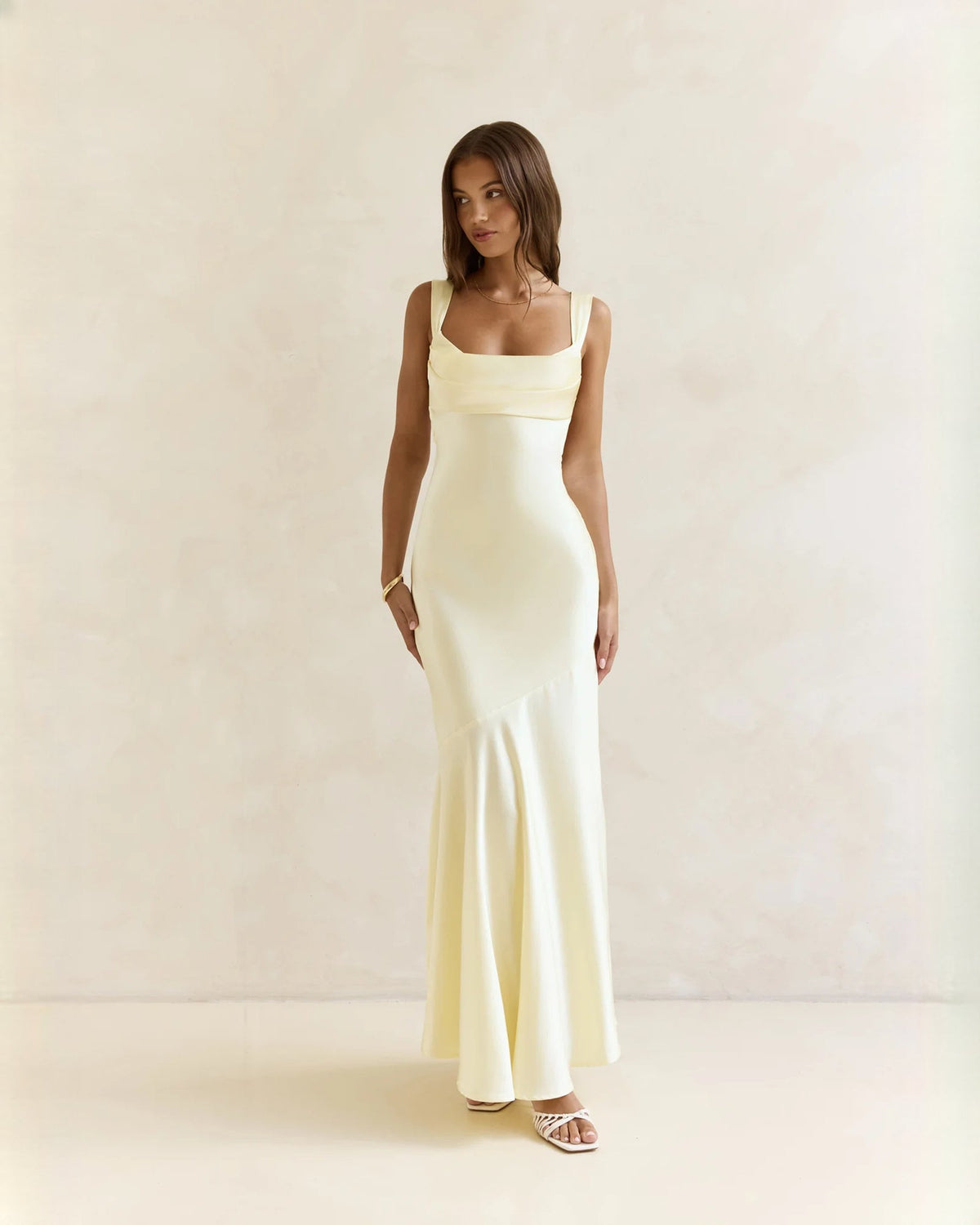 Sleeveless satin A-line maxi dress in pale yellow with thin straps and flowing skirt