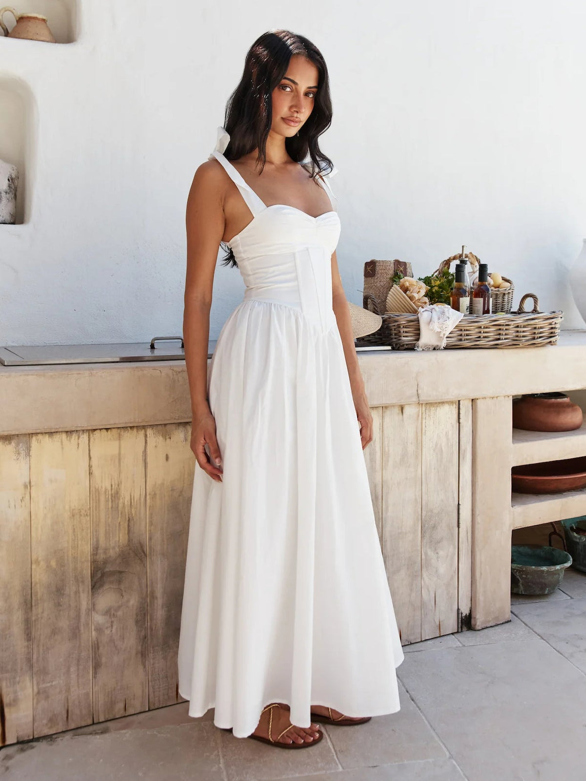 White midi formal dress with bow spaghetti straps, fitted waist, and full gathered skirt.