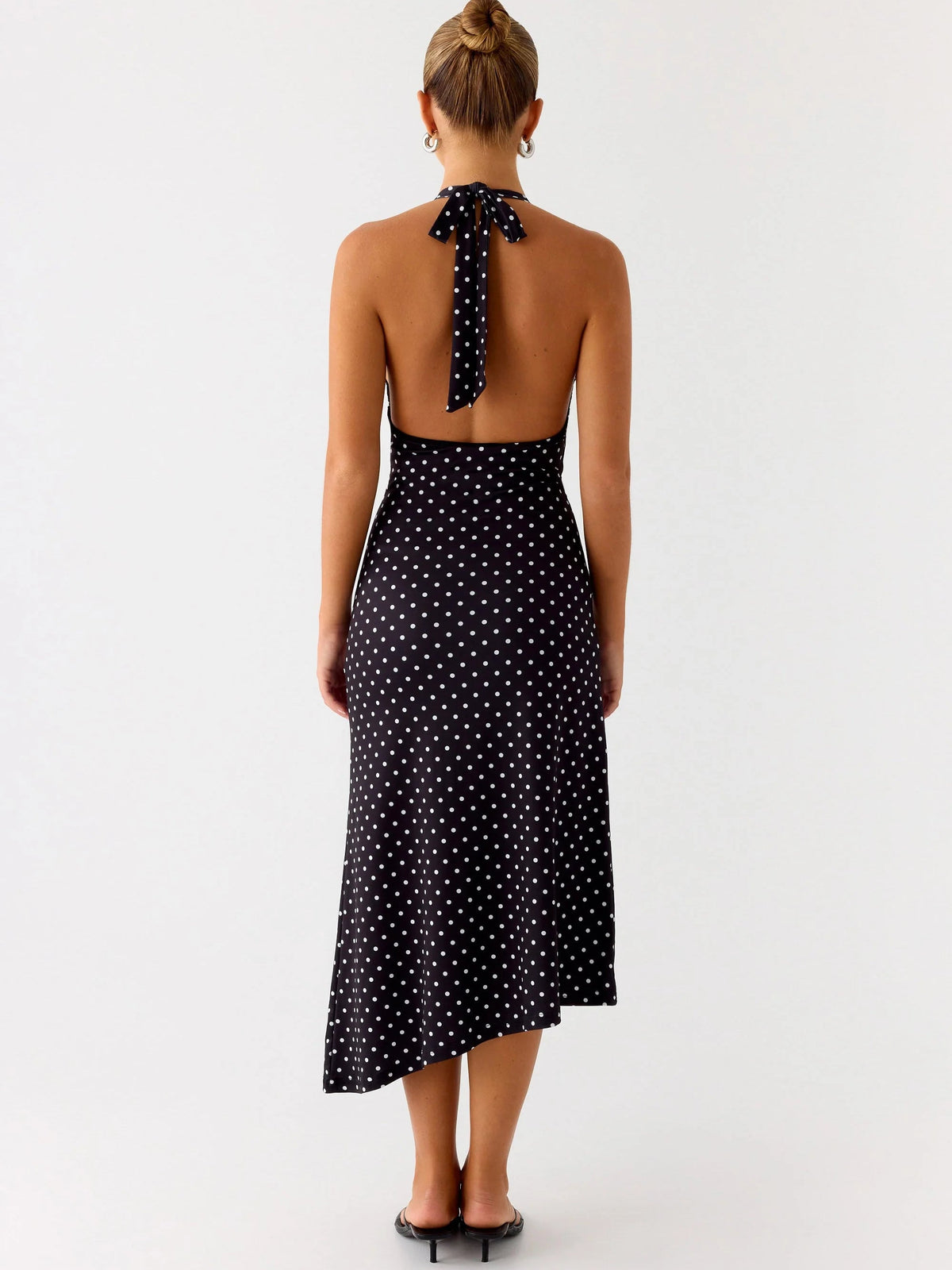 Back view of black polka-dot halter midi dress with open back and tie at neck