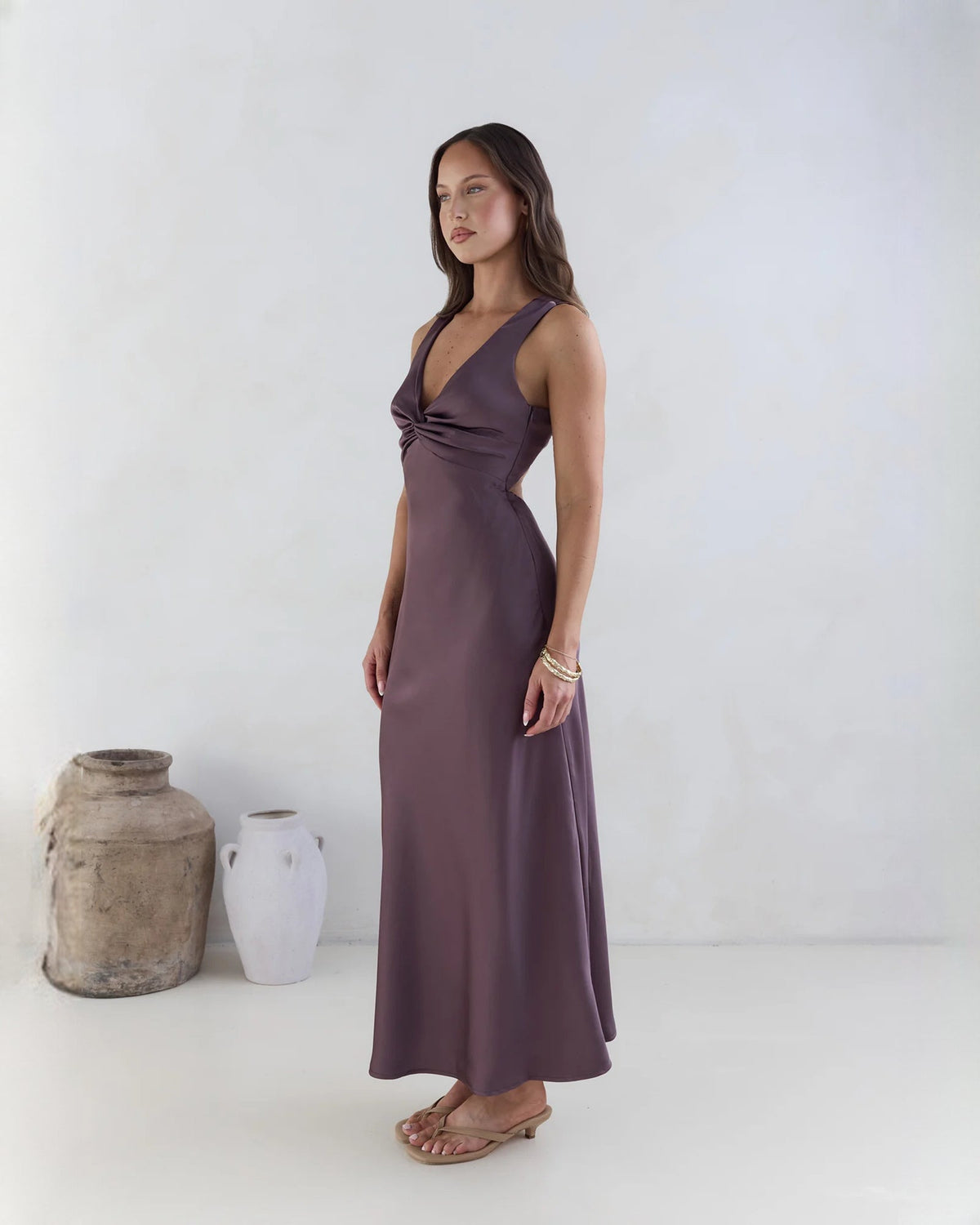 Purple satin sleeveless maxi dress with twisted knot neckline and draped skirt.