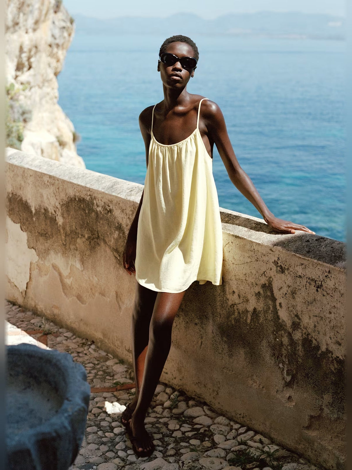 Light yellow mini dress with thin straps and relaxed fit, above-the-knee length