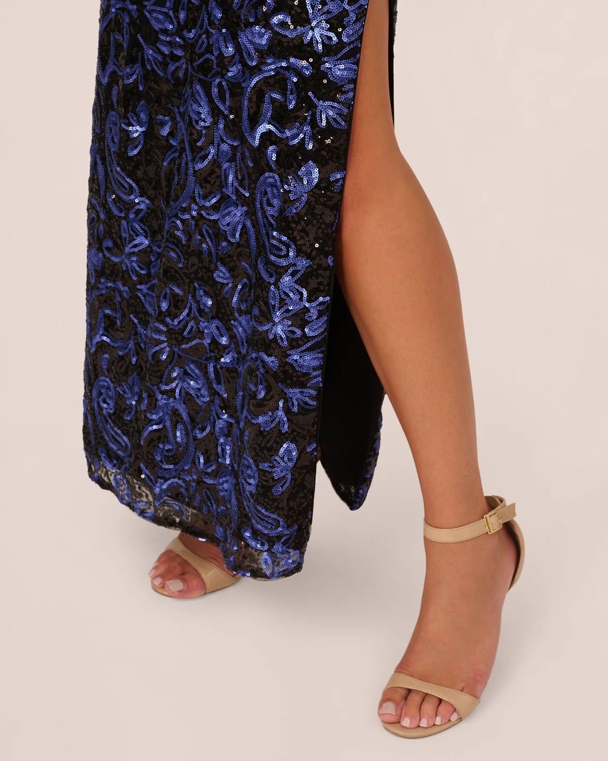 Navy-blue sequin maxi dress with side slit and swirling pattern, feather-trim sleeve
