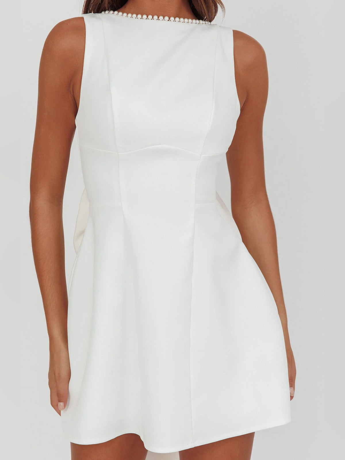 White sleeveless mini dress back view with pearl strap detail and fitted waist