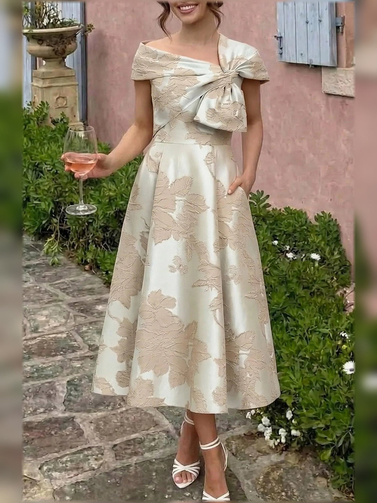 Champagne floral A-line tea-length dress with bow detail and short cap sleeves, outdoors