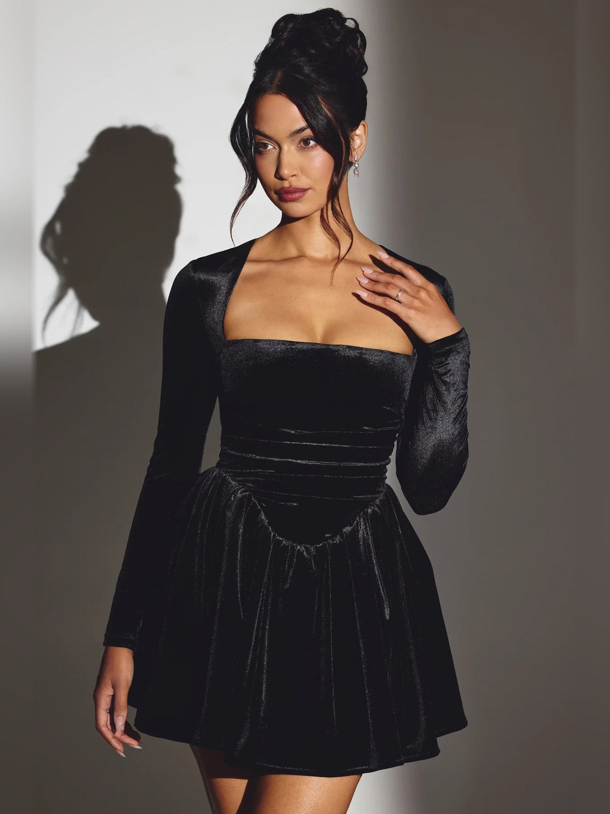 Black velvet corset mini dress with long sleeves and flared skirt, three-quarter view