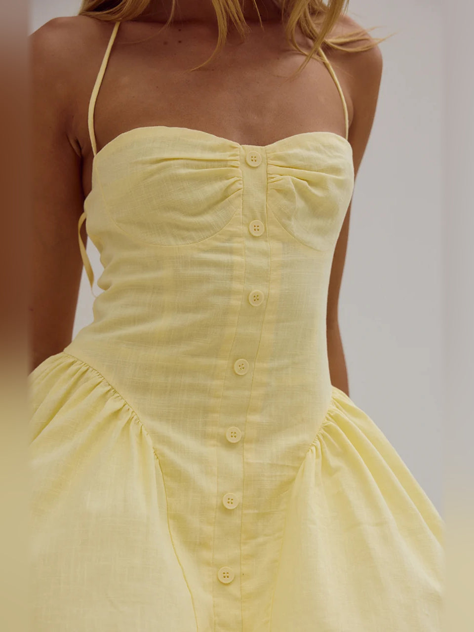 Lemon sweetheart mini dress close-up: buttoned bodice with gathered waist
