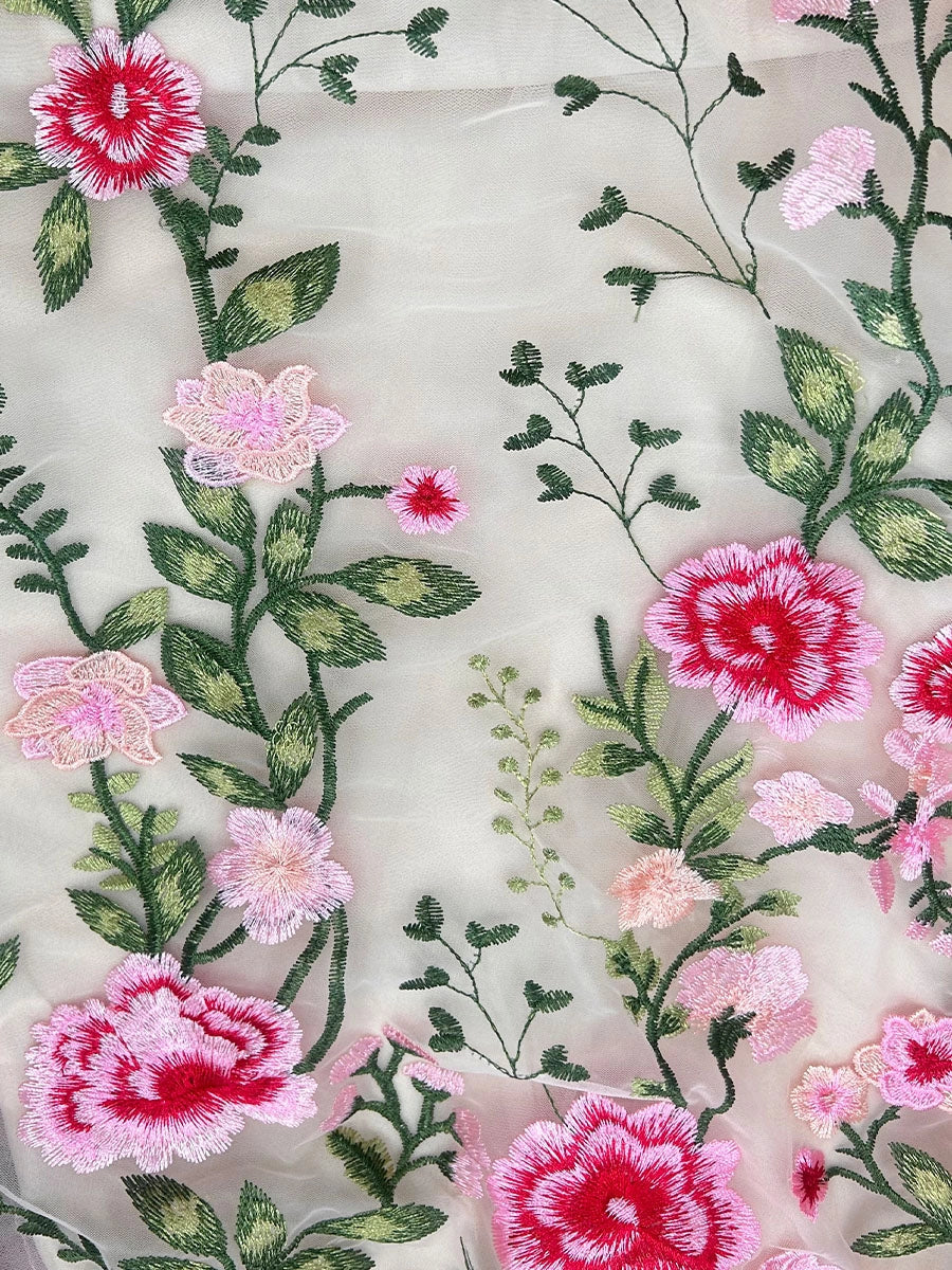 Ivory tulle fabric close-up with layered pink flower embroidery and green leaf vines