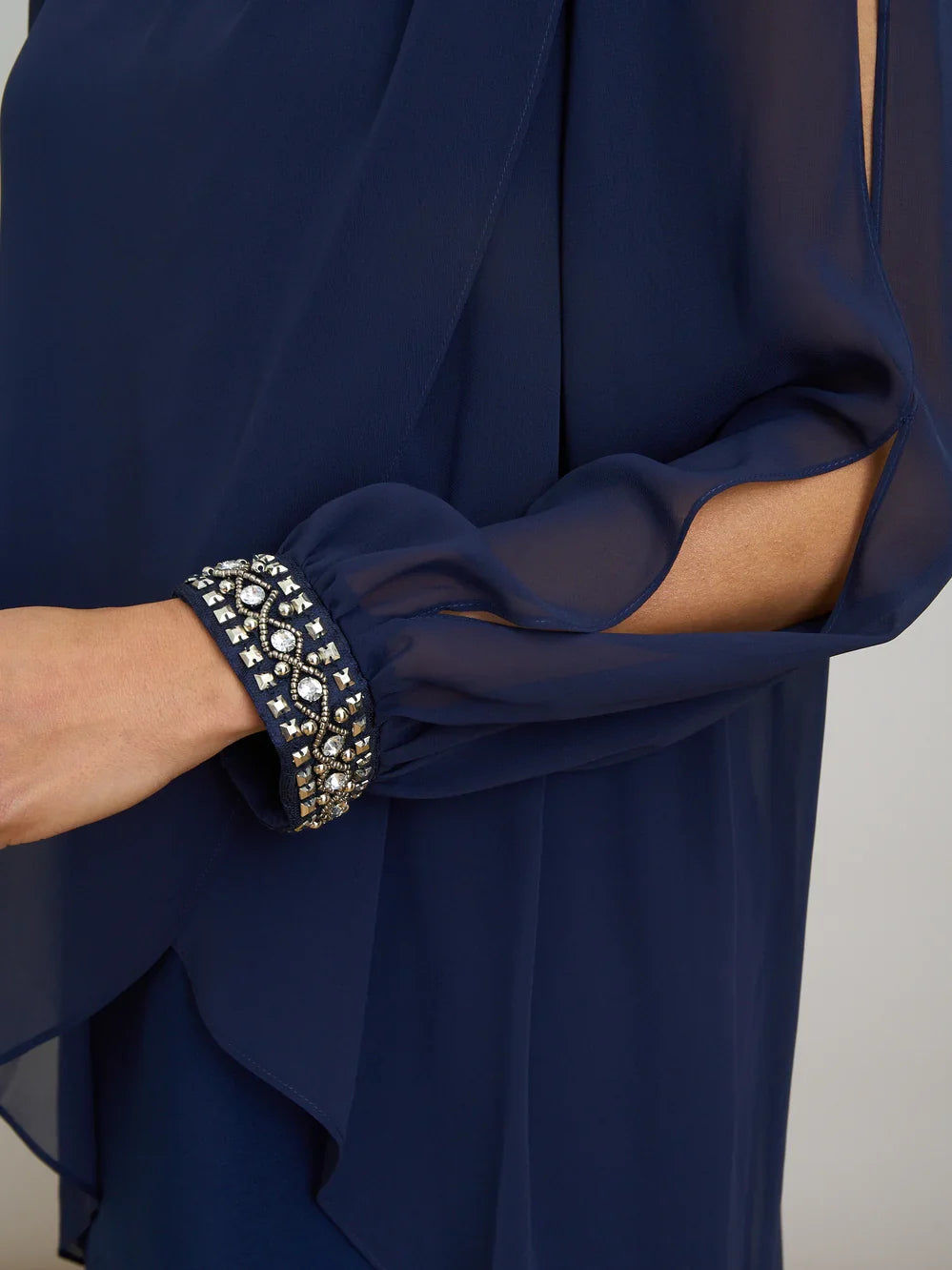Close-up of dark navy chiffon dress with beaded cuff detail and layered draped overlay