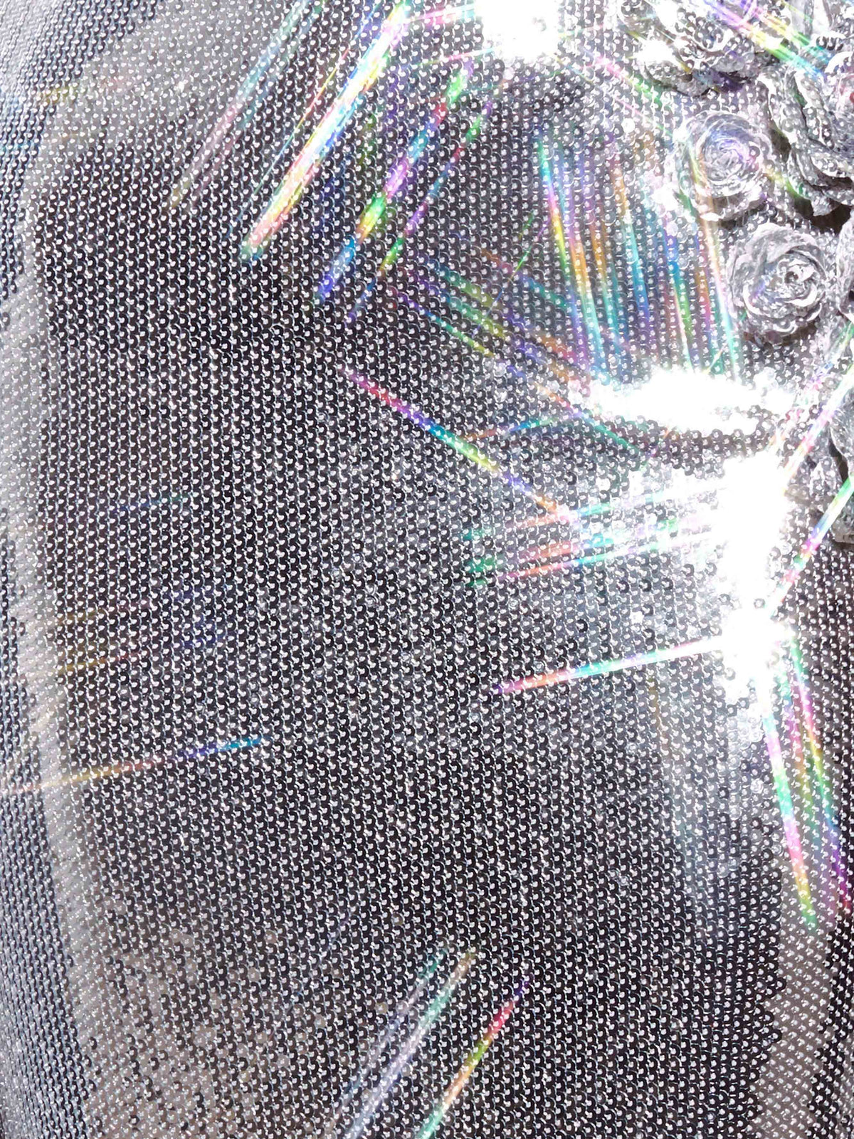 Close-up of silver sequin fabric with floral rosette embellishment