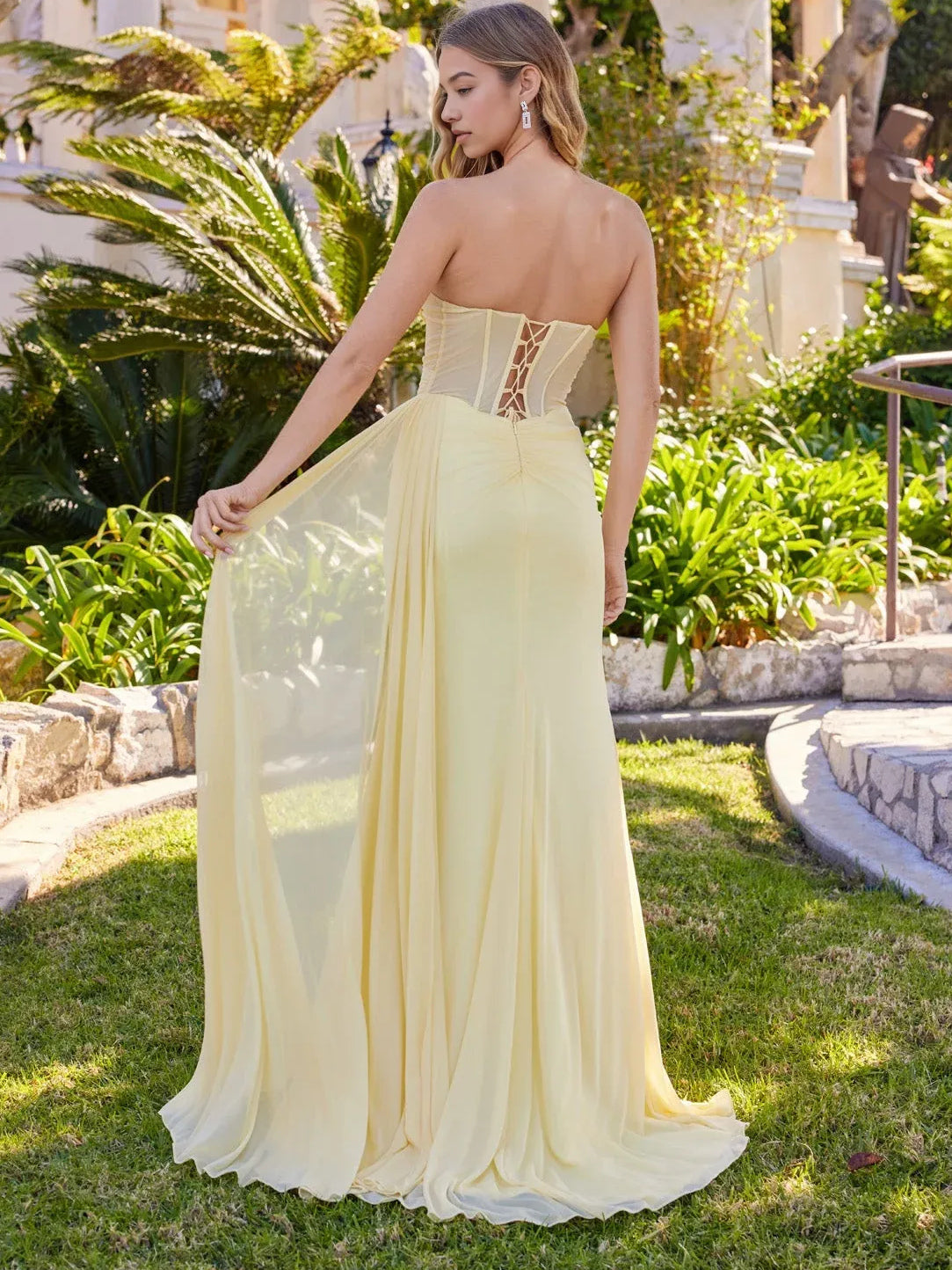 Pale yellow corset-back prom dress with lace-up panel and flowing long skirt
